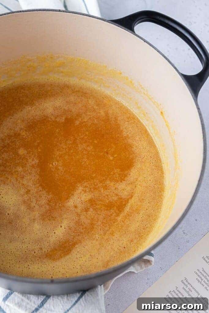 Peach puree gently simmering in a pot on the stovetop, extracting maximum flavor.