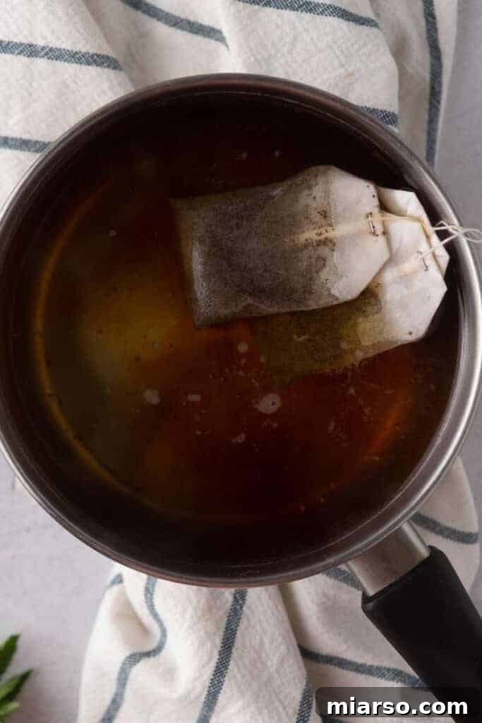 Black tea bags steeping in hot water, forming the foundation of the iced tea.