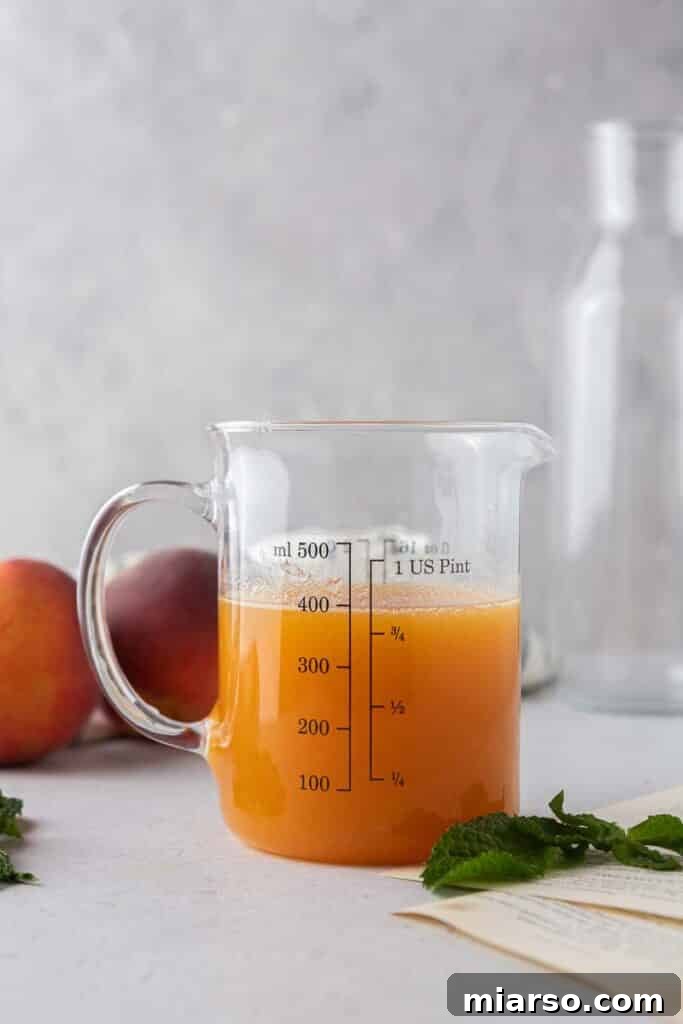 Homemade peach syrup collected in a glass, ready to be combined with the chilled black tea.