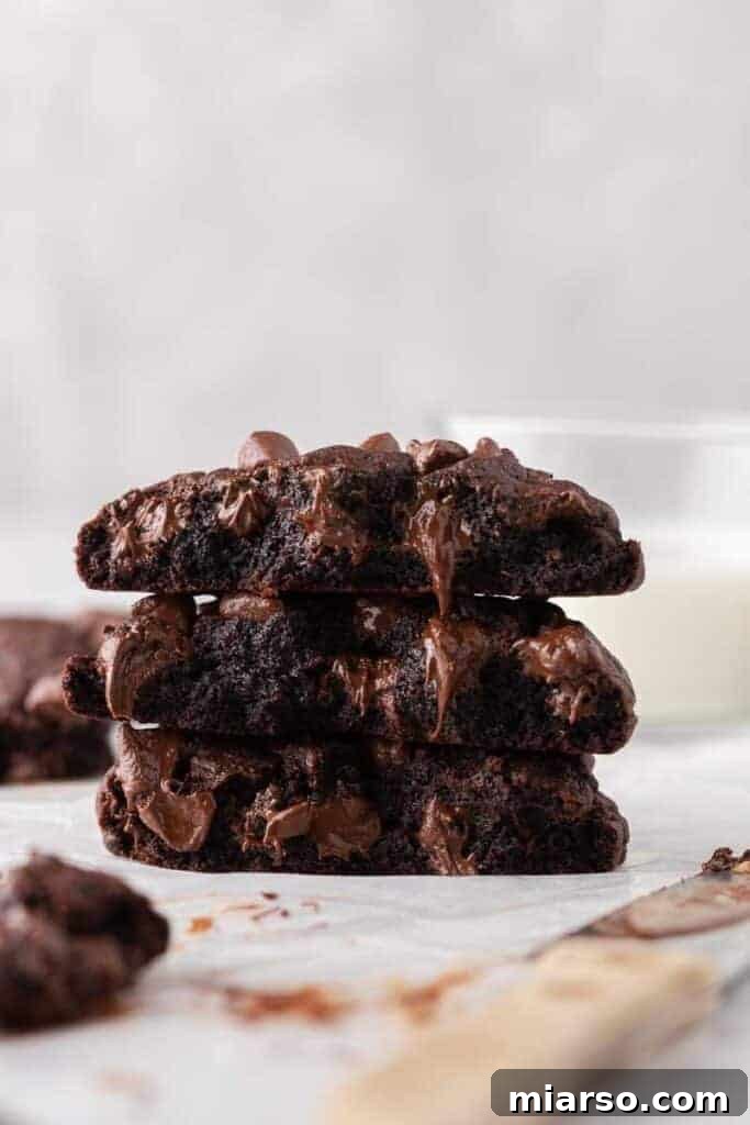 Stack of soft Crumbl dark dream double chocolate cookies with melted chocolate chips and gooey centers.
