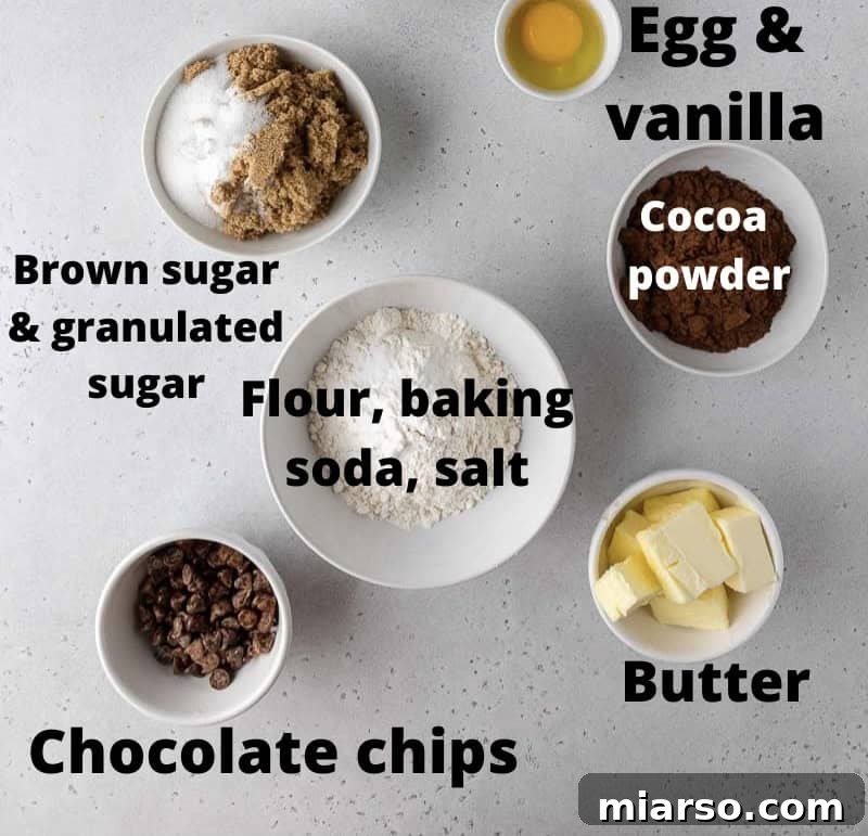 Ingredients laid out for Crumbl dark dream cookies including butter, sugar, flour, cocoa powder, egg, vanilla, and chocolate chips.
