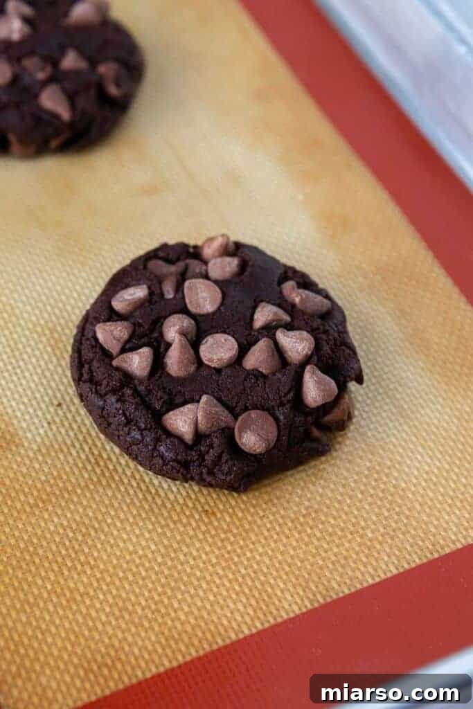 Freshly baked thick chocolate chip cookie on silicone baking mat.