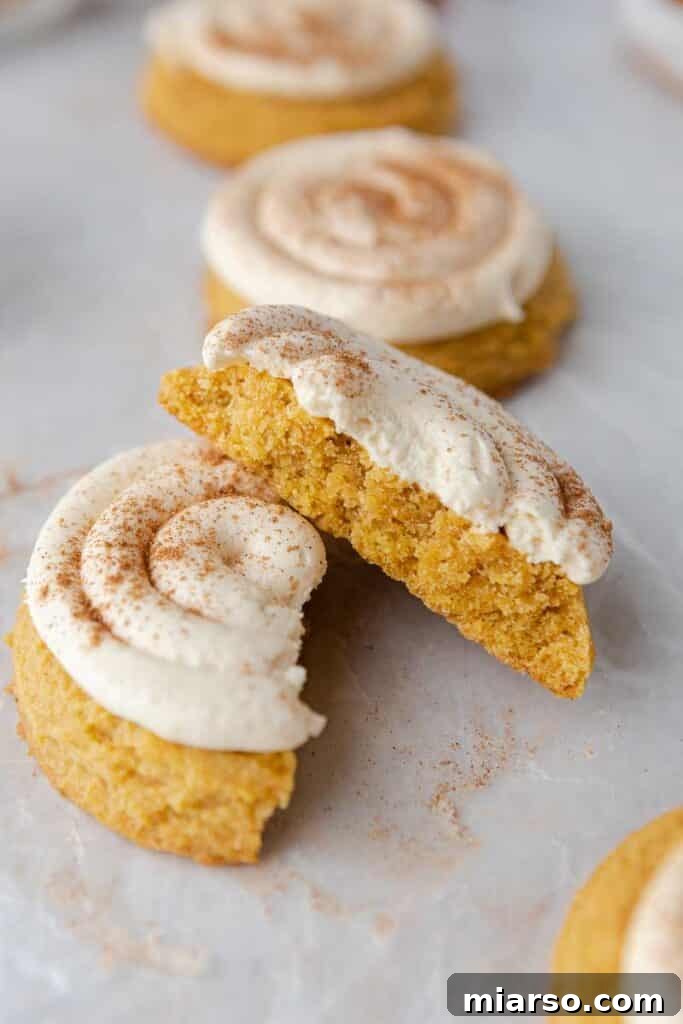 Crumbl Caramel Pumpkin cookies split in half, showcasing the soft interior and creamy frosting.