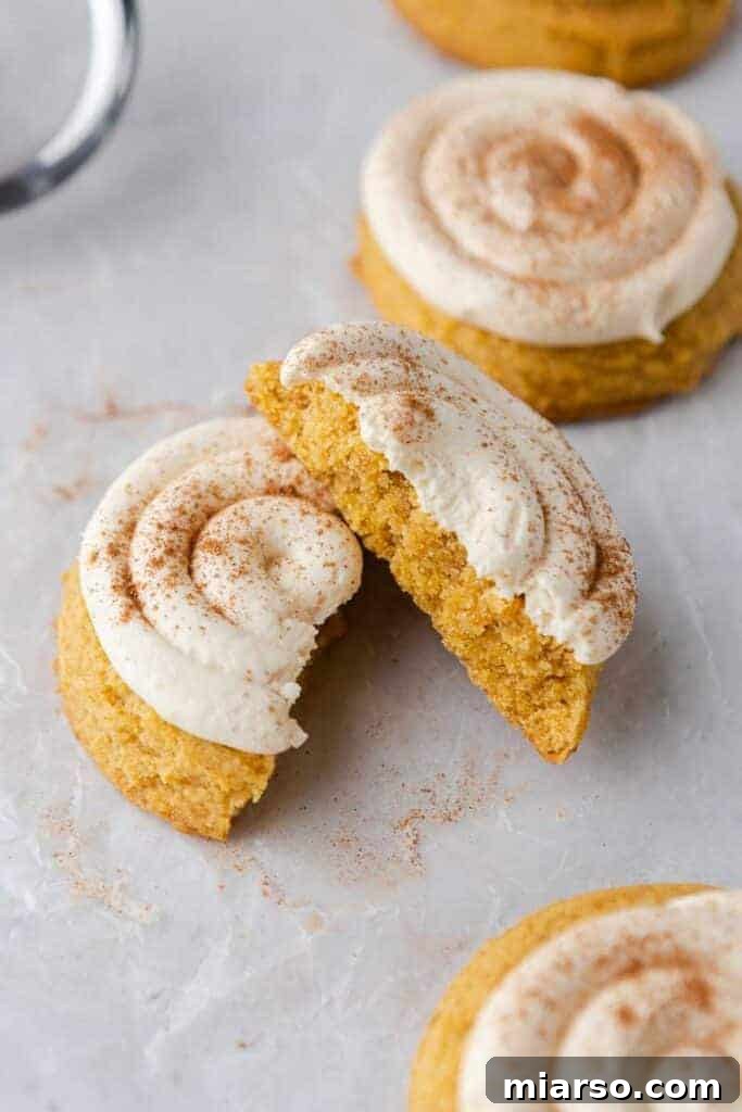 Fully frosted Crumbl caramel pumpkin cookies with pumpkin pie spice dusting.