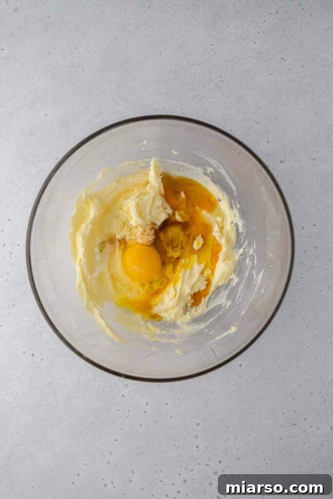 Close-up of butter, granulated sugar, and powdered sugar being creamed together in a bowl