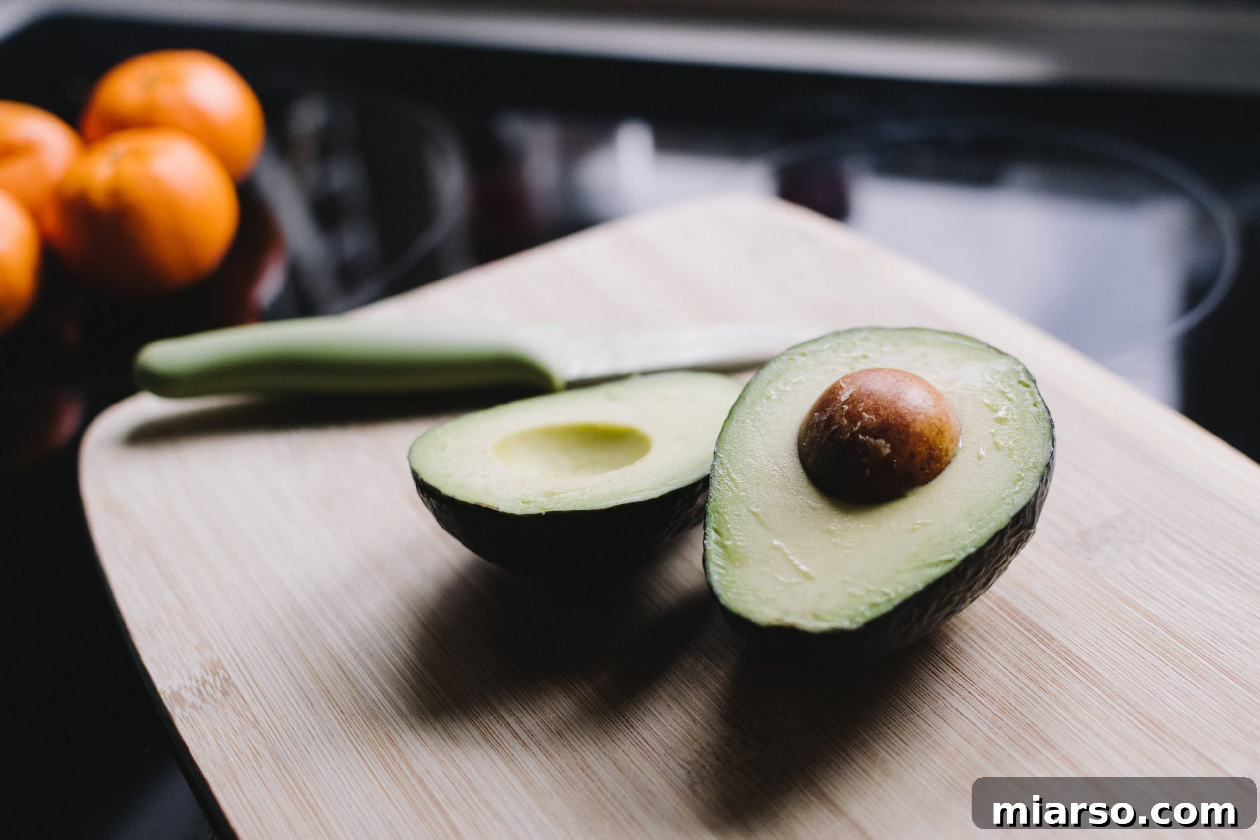 sliced avocado with oranges in the background