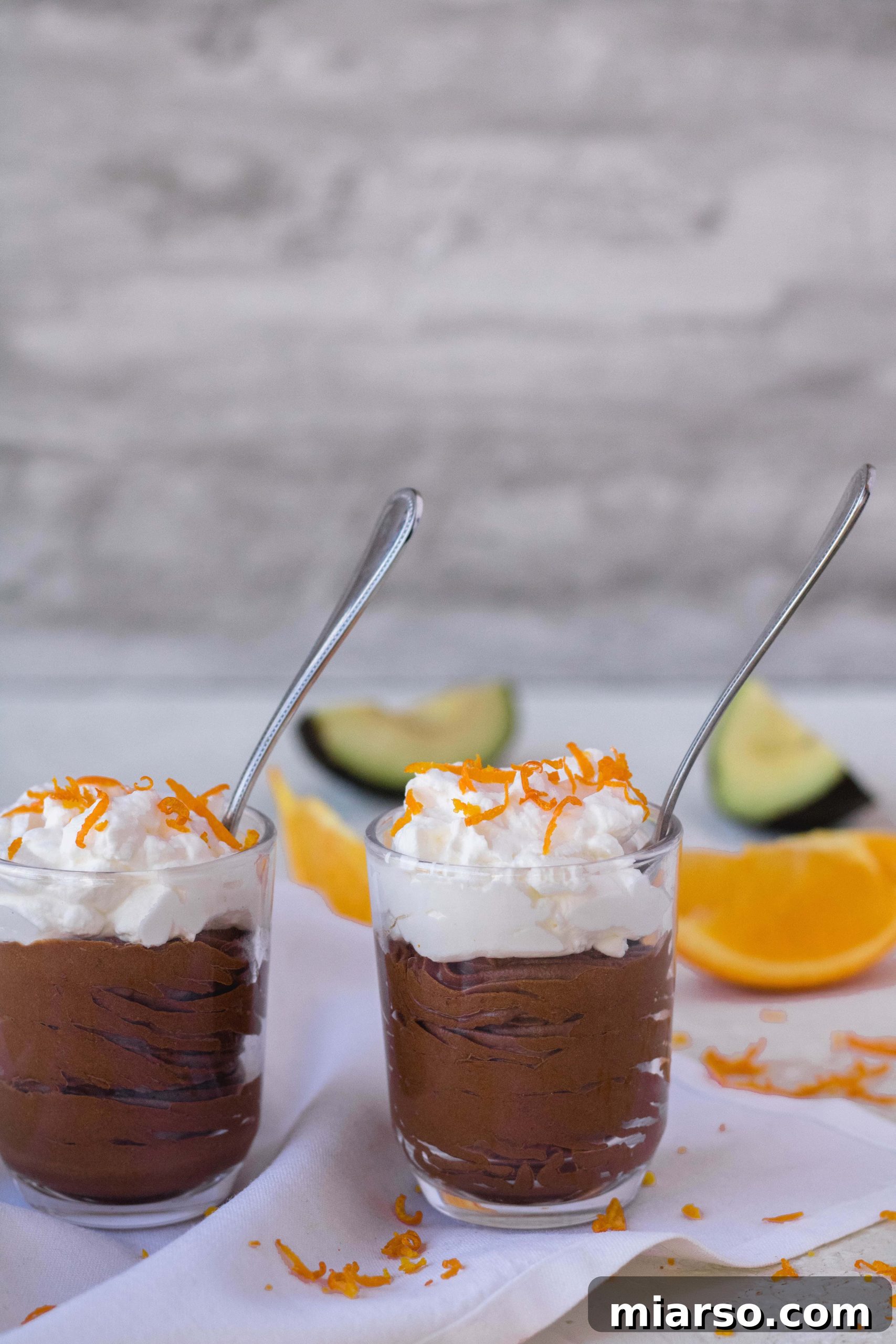 Two vegan avocado chocolate mousse cups with spoons