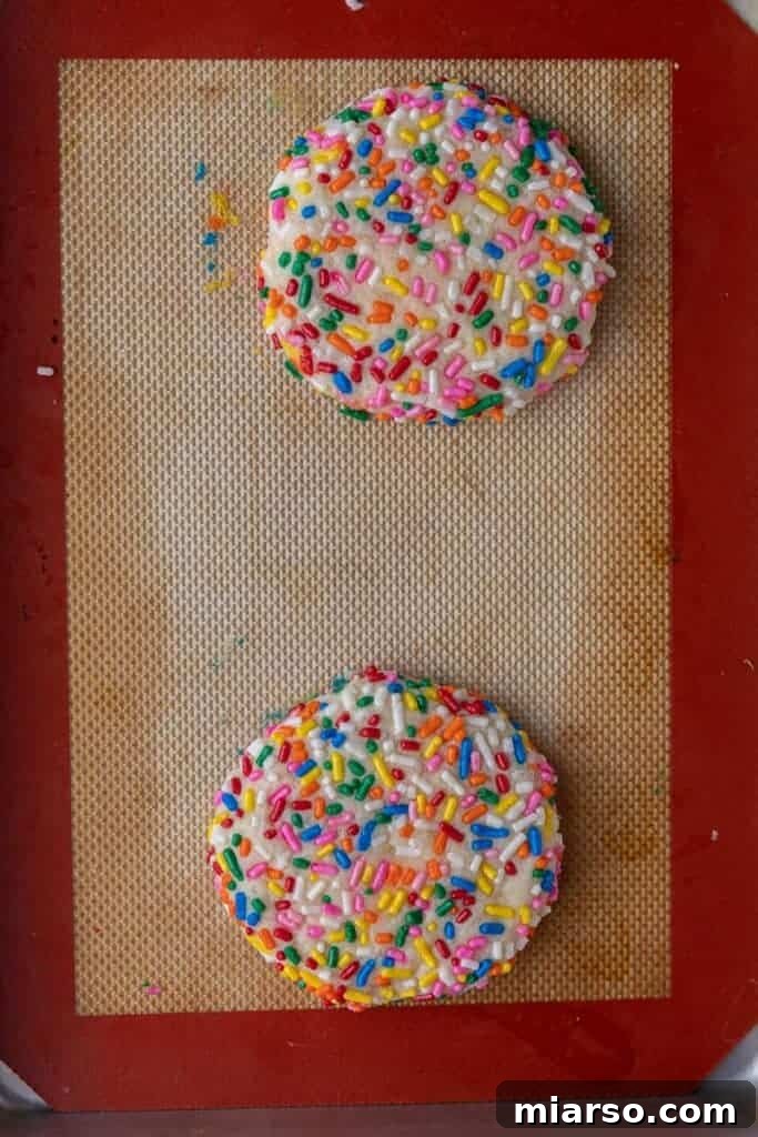 Freshly baked funfetti cookies on a baking sheet, cooling.