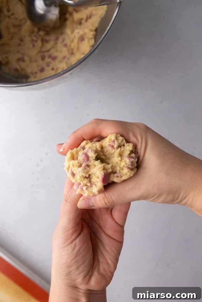 Close-up of a raw cookie dough ball with visible ruby chocolate chips
