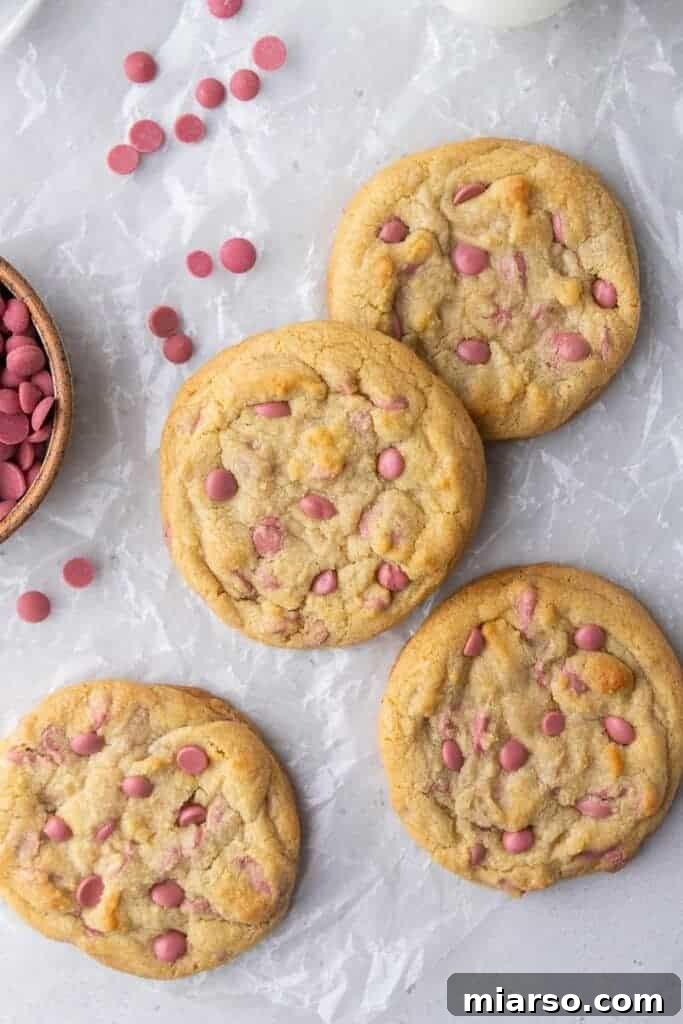 Perfectly round, thick Crumbl ruby chocolate chip cookies on a cooling rack