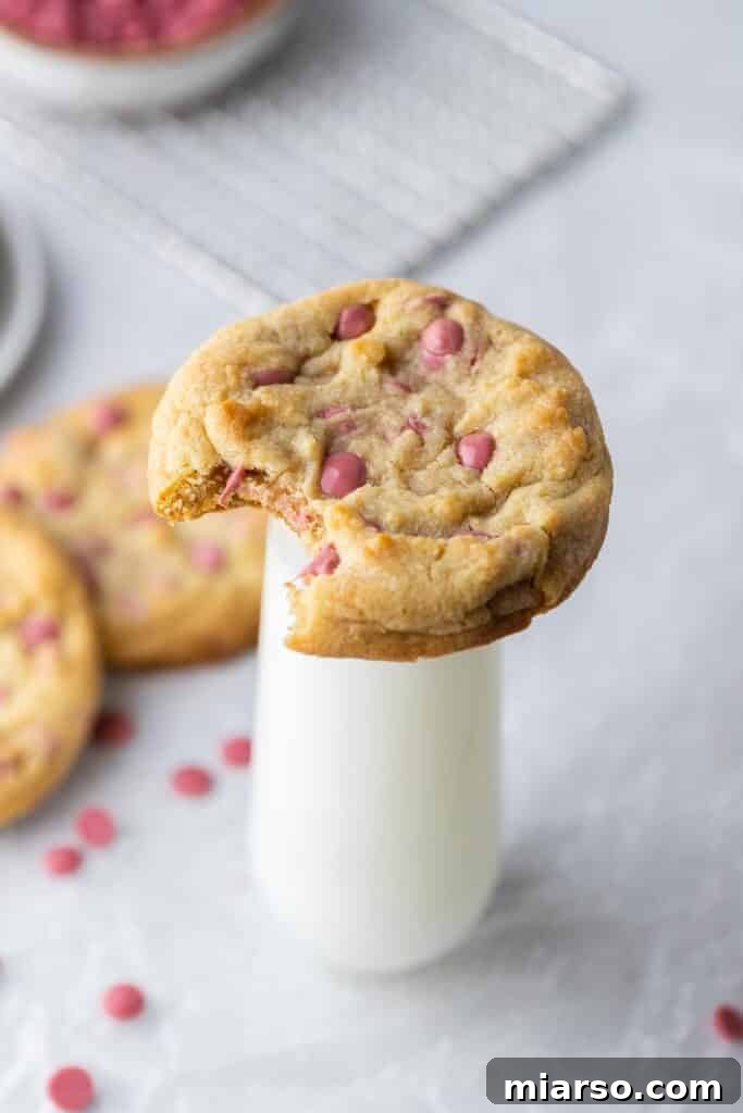 Thick ruby chocolate chip cookie propped on a milk glass, highlighting its impressive size