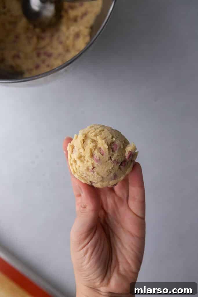 Hand demonstrating the method of splitting cookie dough in half before pressing back together to create jagged edges
