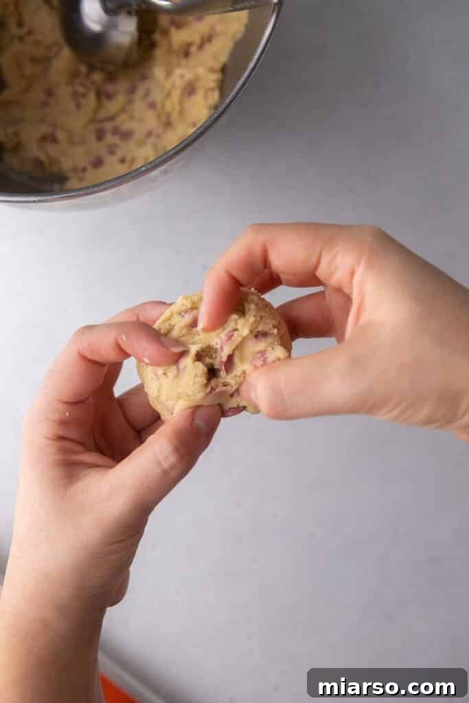 Cookie dough with ruby chocolate chips on a baking sheet, showing the jagged-edge technique