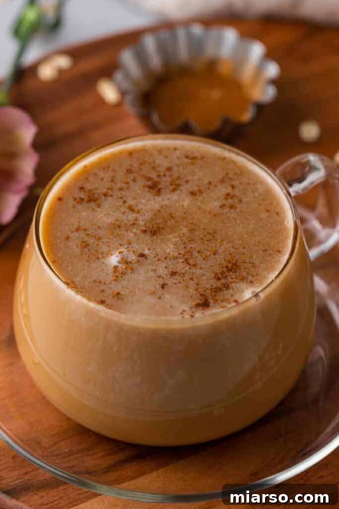A beautifully presented honey oat milk latte, a perfect Starbucks copycat, served in a clear glass mug with ice and a sprinkle of cinnamon, against a warm, inviting background.