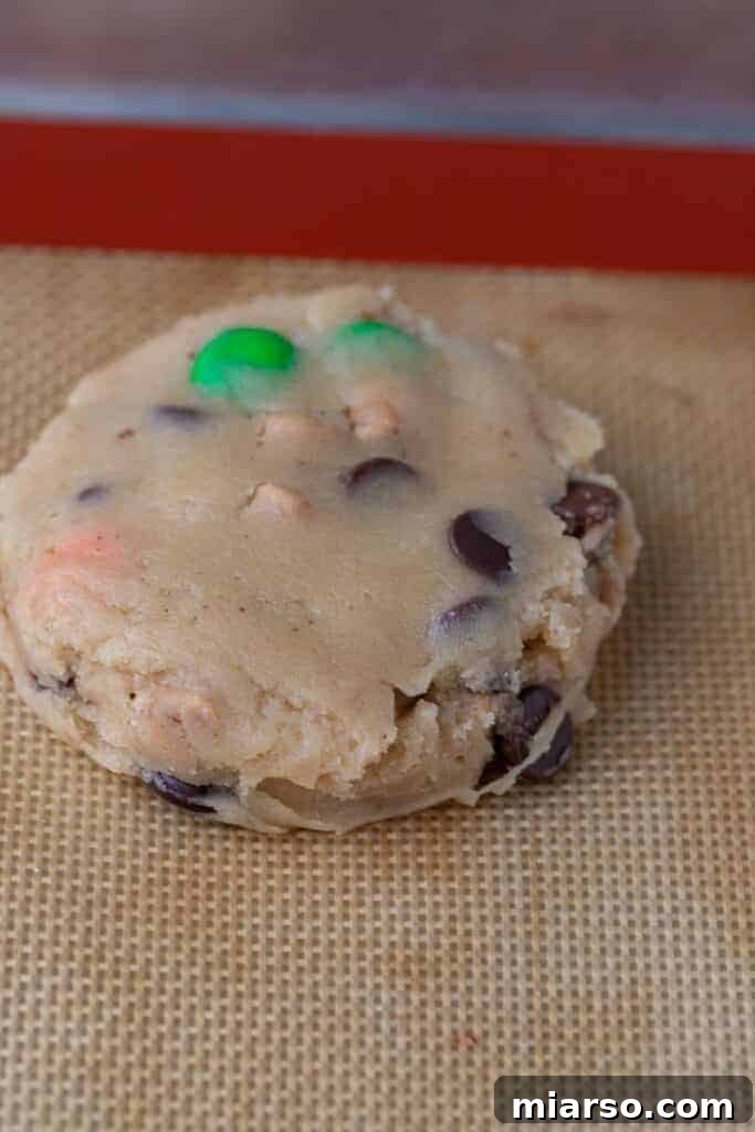 Freshly baked Crumbl Monster Cookies cooling on a baking sheet.
