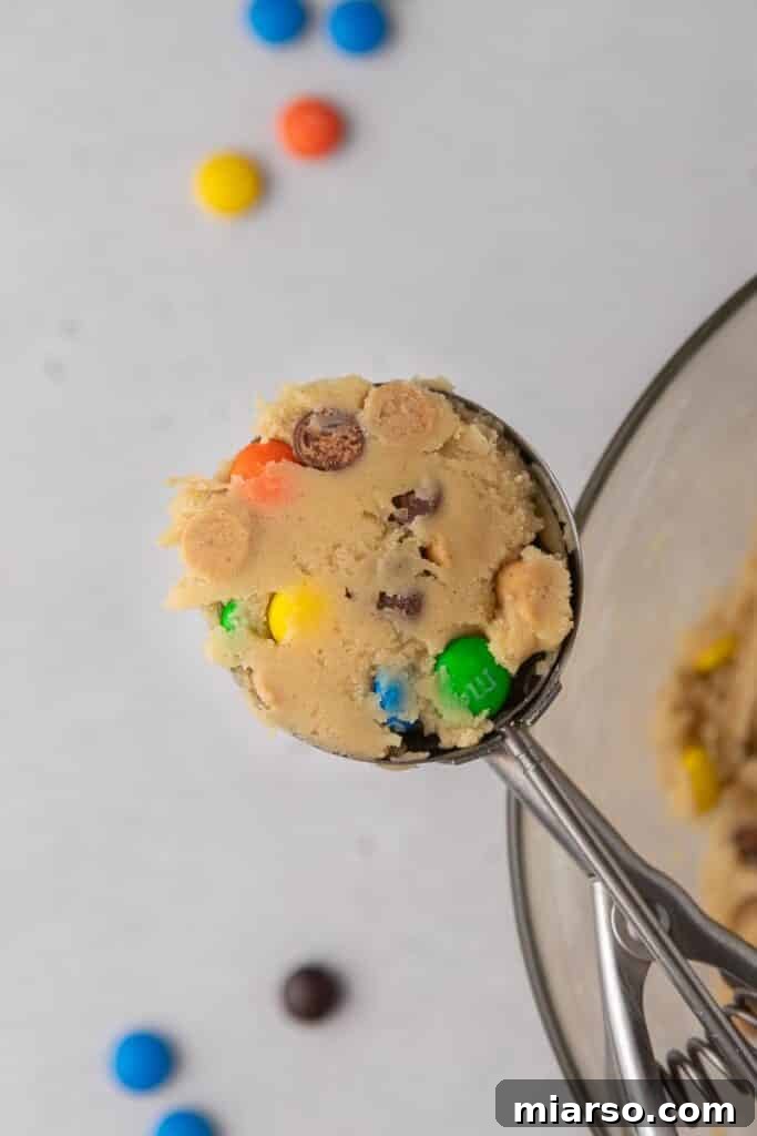 Crumbl Monster Cookies being scooped onto a baking sheet.