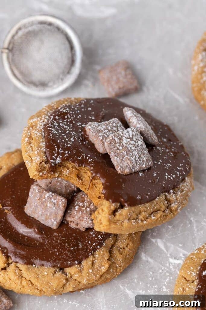 A Crumbl Muddy Buddies cookie showing the detailed topping of melted chocolate, Muddy Buddies, and powdered sugar.