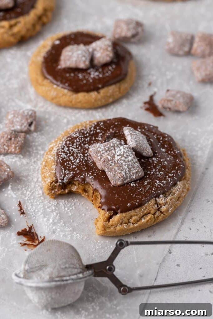Pile of Crumbl Peanut Butter Muddy Buddies cookies on a plate.