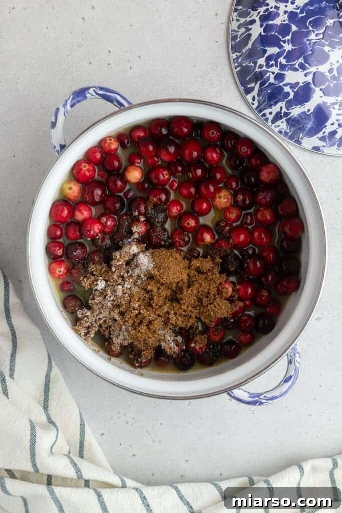 Cranberry sauce ingredients simmering in a medium pot.