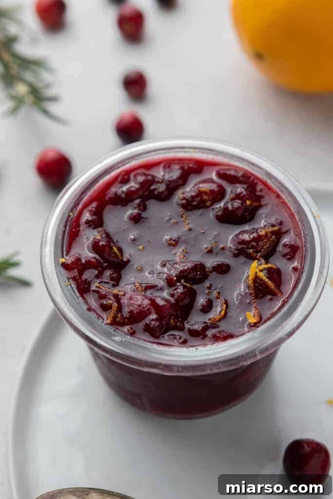 A bowl of homemade cranberry sauce with oranges, garnished with fresh orange slices.