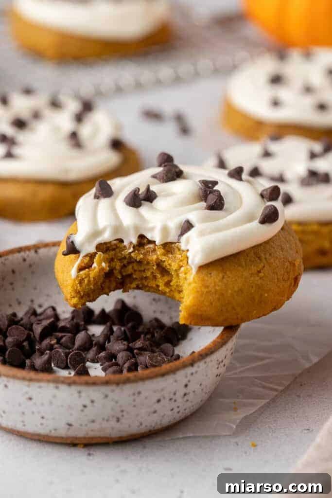 Crumbl pumpkin cake cookie with a bite taken out of it, a moist and delicious fall treat.