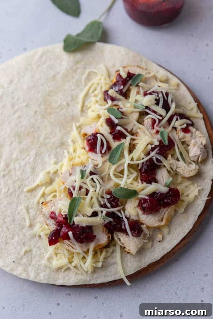 Open faced turkey quesadilla on a skillet, showing layers of turkey, cheese, and cranberry sauce.