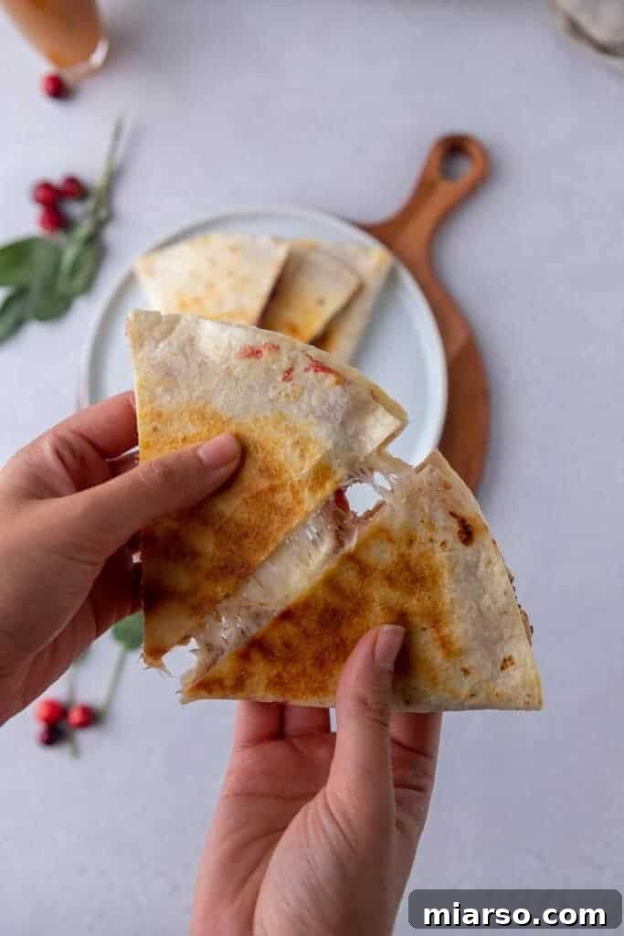 Two golden-brown Thanksgiving leftover quesadillas on a cutting board, ready to be sliced.