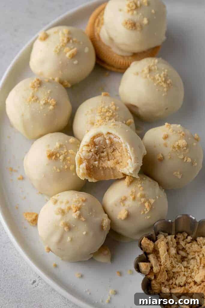 Golden Oreo Cheesecake Truffles 7 Freshly dipped white chocolate Golden Oreo truffles on a baking sheet.