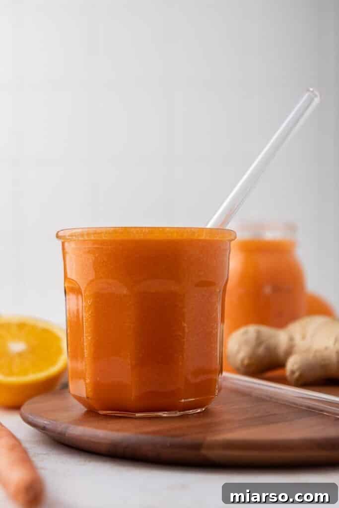 Golden Immunity Zest Smoothie 2 Vibrant ginger carrot orange smoothie in a tall glass, garnished with fresh orange slices, ready to drink.