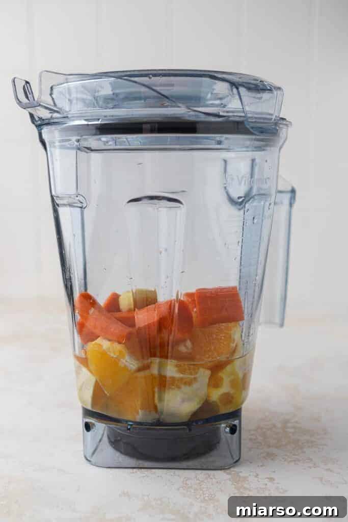 Golden Immunity Zest Smoothie 4 Fresh oranges, carrots, and ginger being added to a Vitamix blender, ready for blending.