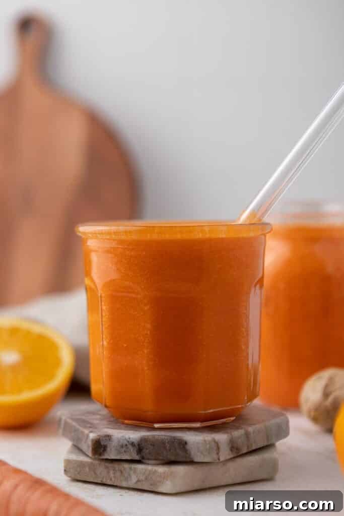 Golden Immunity Zest Smoothie 5 A bright orange ginger carrot orange smoothie poured into a glass, showcasing its smooth texture and vibrant color.