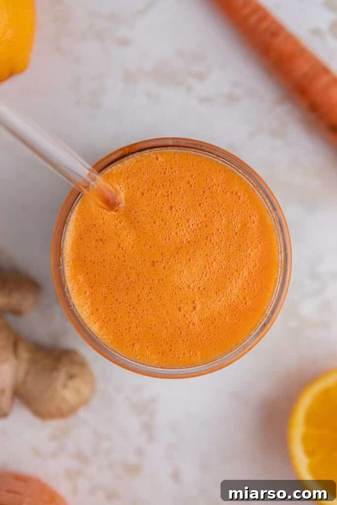 Golden Immunity Zest Smoothie 6 An overhead shot of a ginger carrot orange smoothie in a glass, with fresh orange slices and ginger in the background, highlighting its inviting color.