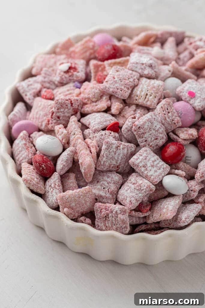 Cupid's Crunch 2 Festive Valentine's Day Muddy Buddies in a bowl, showcasing pink and red cereal with M&M's and heart sprinkles.