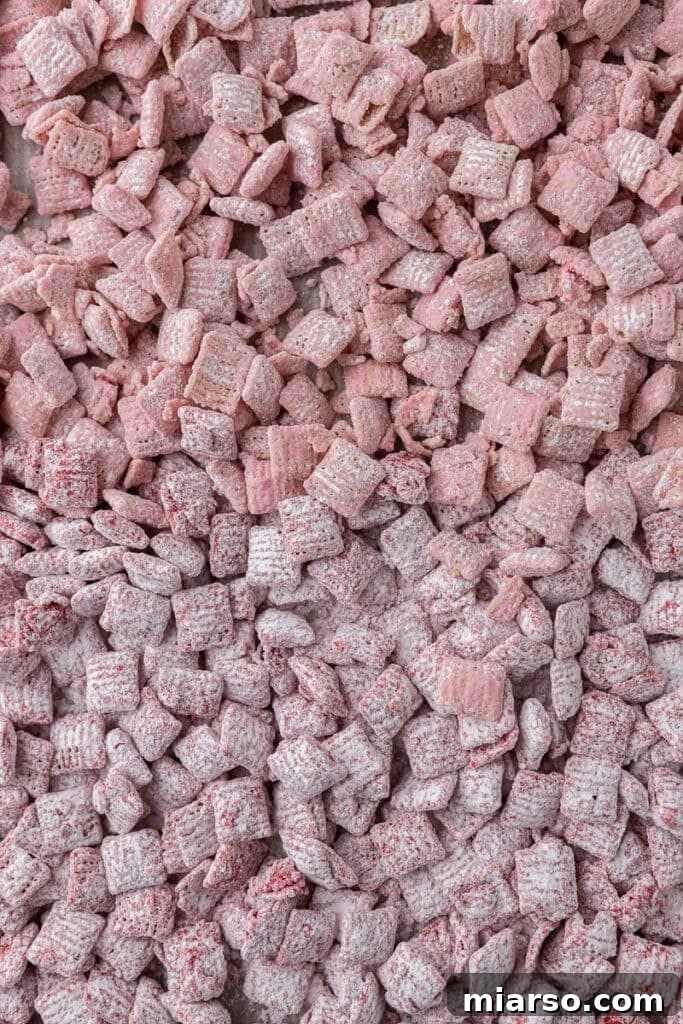 Cupid's Crunch 13 Mixed Valentine's Day muddy buddies, pink and red, spread on a baking sheet to set.