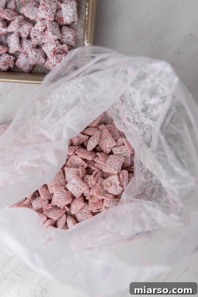 Cupid's Crunch 7 Freshly coated pink muddy buddies spread out on wax paper to set.