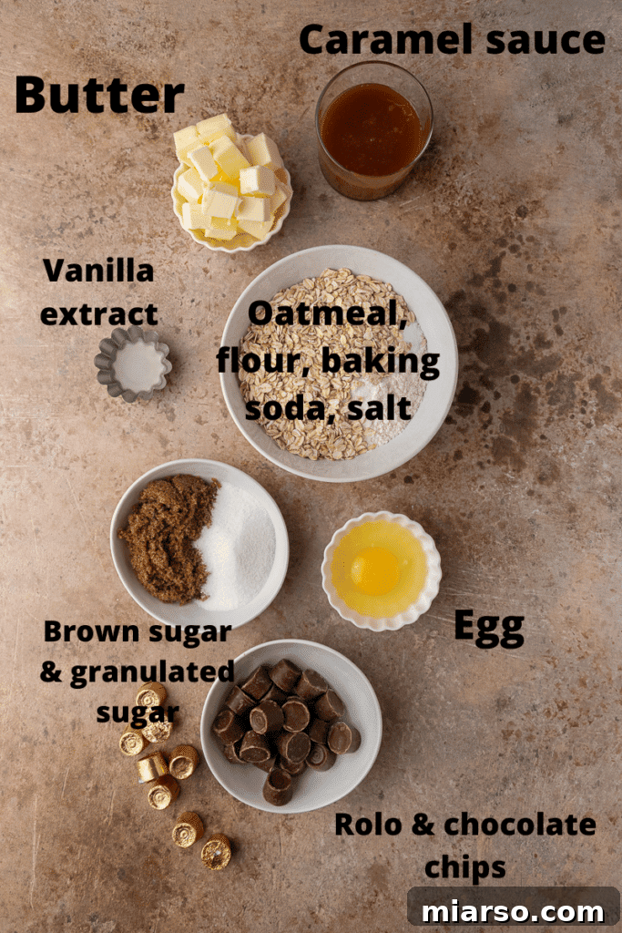 A flat lay of ingredients for Crumbl Oatmeal Rolo Cookies including butter, sugars, oats, flour, eggs, Rolo candies, and chocolate chips