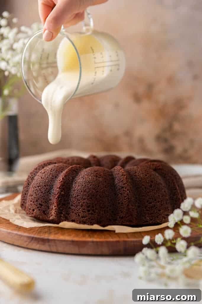 Hand pouring glaze over bundt cake
