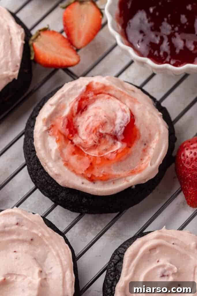 Close-up of a single Oreo strawberry cheesecake cookie, showing the rich dark base and luscious pink frosting.