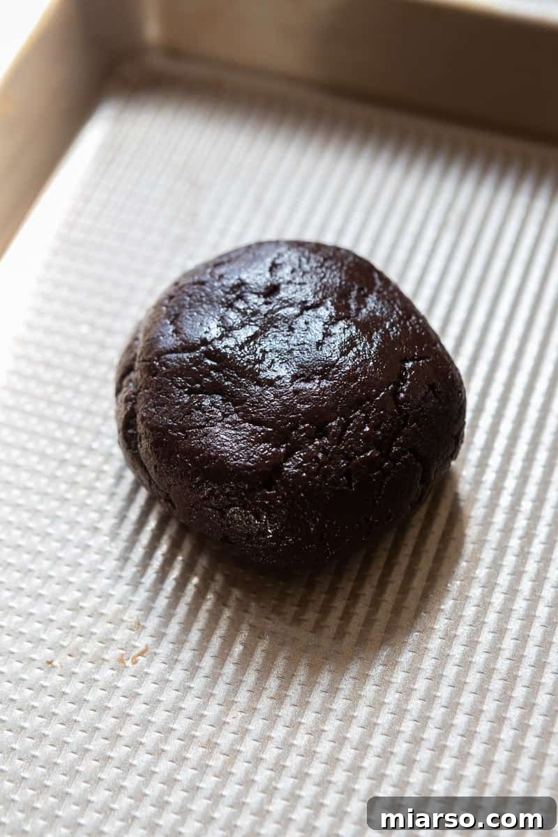 Unbaked chocolate cookie dough balls on a baking sheet
