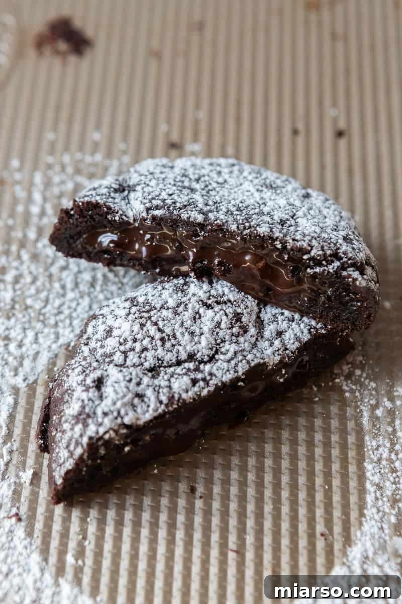A Crumbl Molten Lava Cookie broken in half, revealing the gooey chocolate center