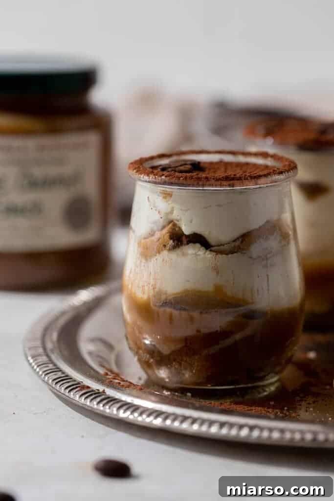 Layers of ladyfingers, caramel, and mascarpone cream in a glass cup