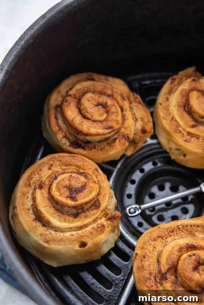Pillsbury cinnamon rolls arranged neatly in an air fryer basket, ready for cooking.