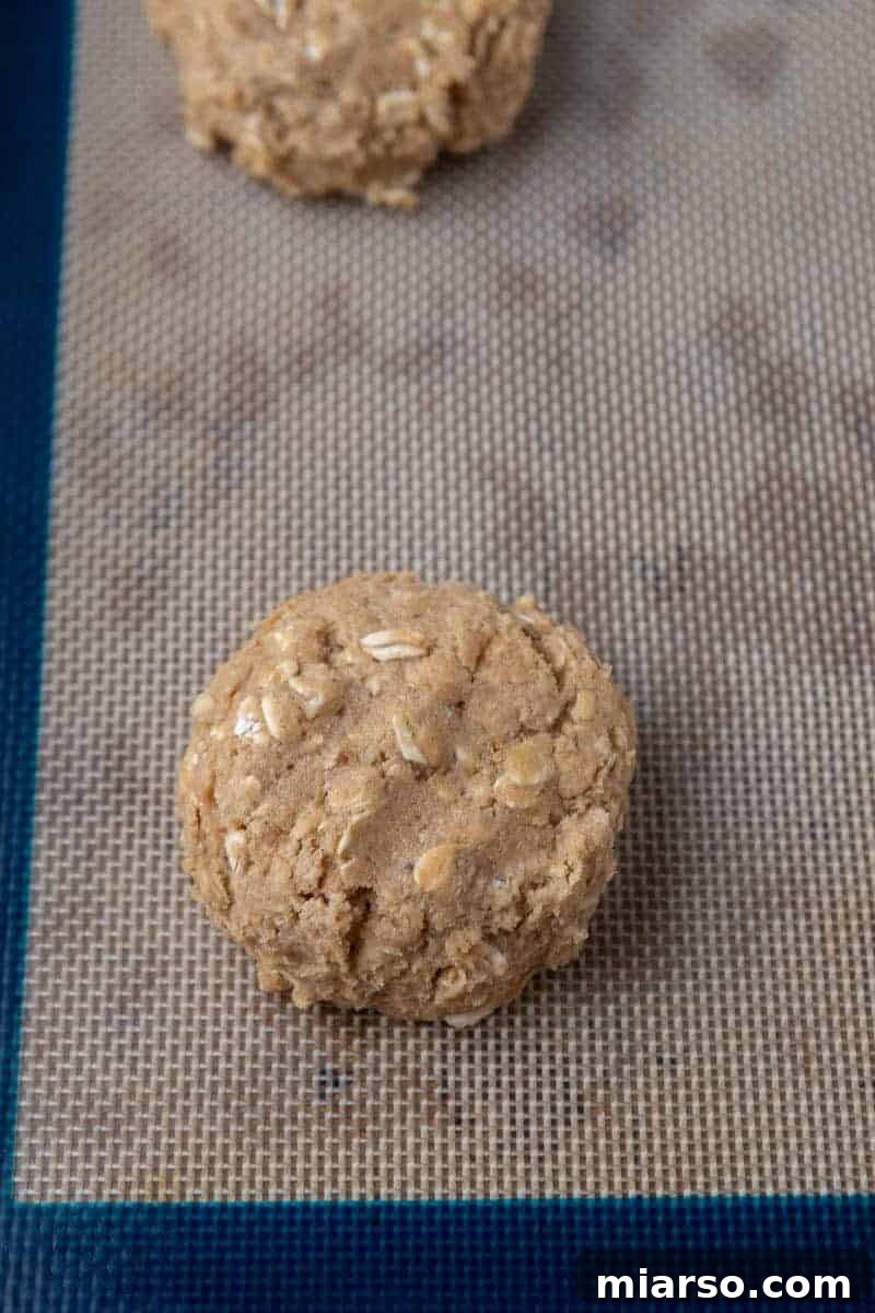 Scooped portions of oatmeal cookie dough on a baking sheet, pressed slightly.