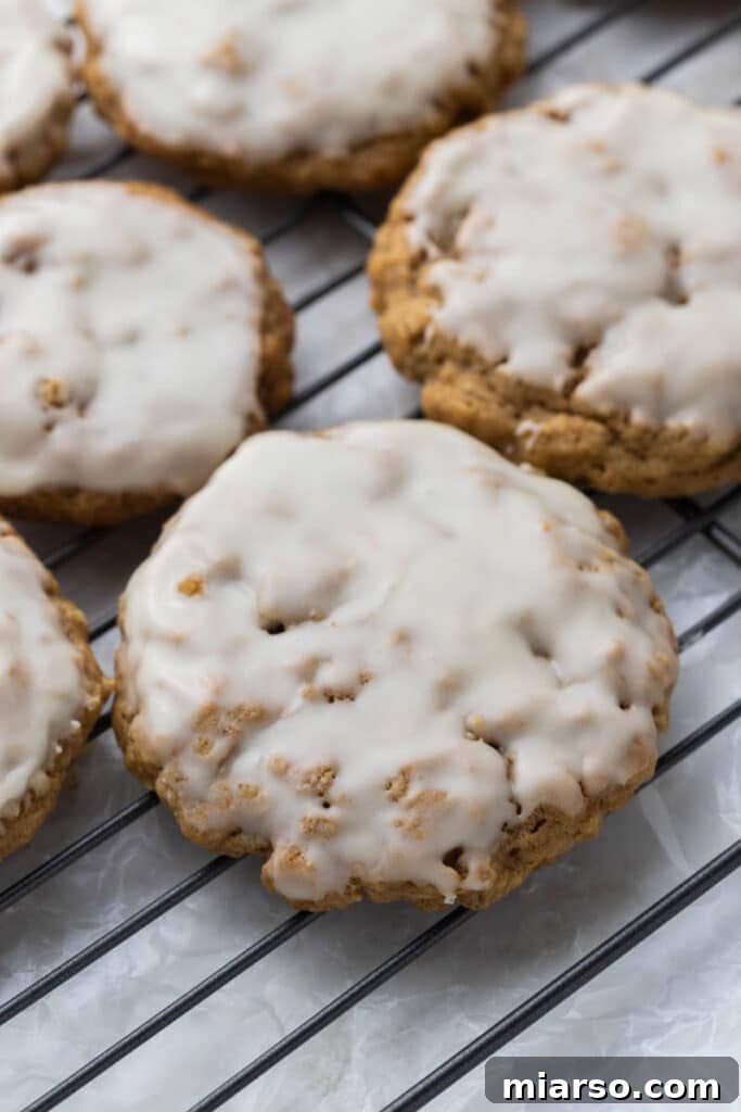 Iced oatmeal cookies arranged on a cooling rack, allowing the vanilla glaze to set.