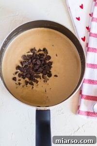 Adding the chocolate chips to the peanut butter and coconut oil