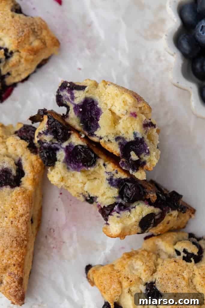 Close-up of a cut blueberry scone, showing its moist interior and generous blueberries.