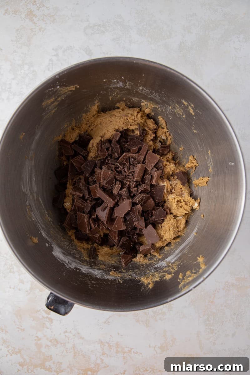 Cookie dough with a generous amount of chocolate chunks folded in, resting in a mixing bowl.