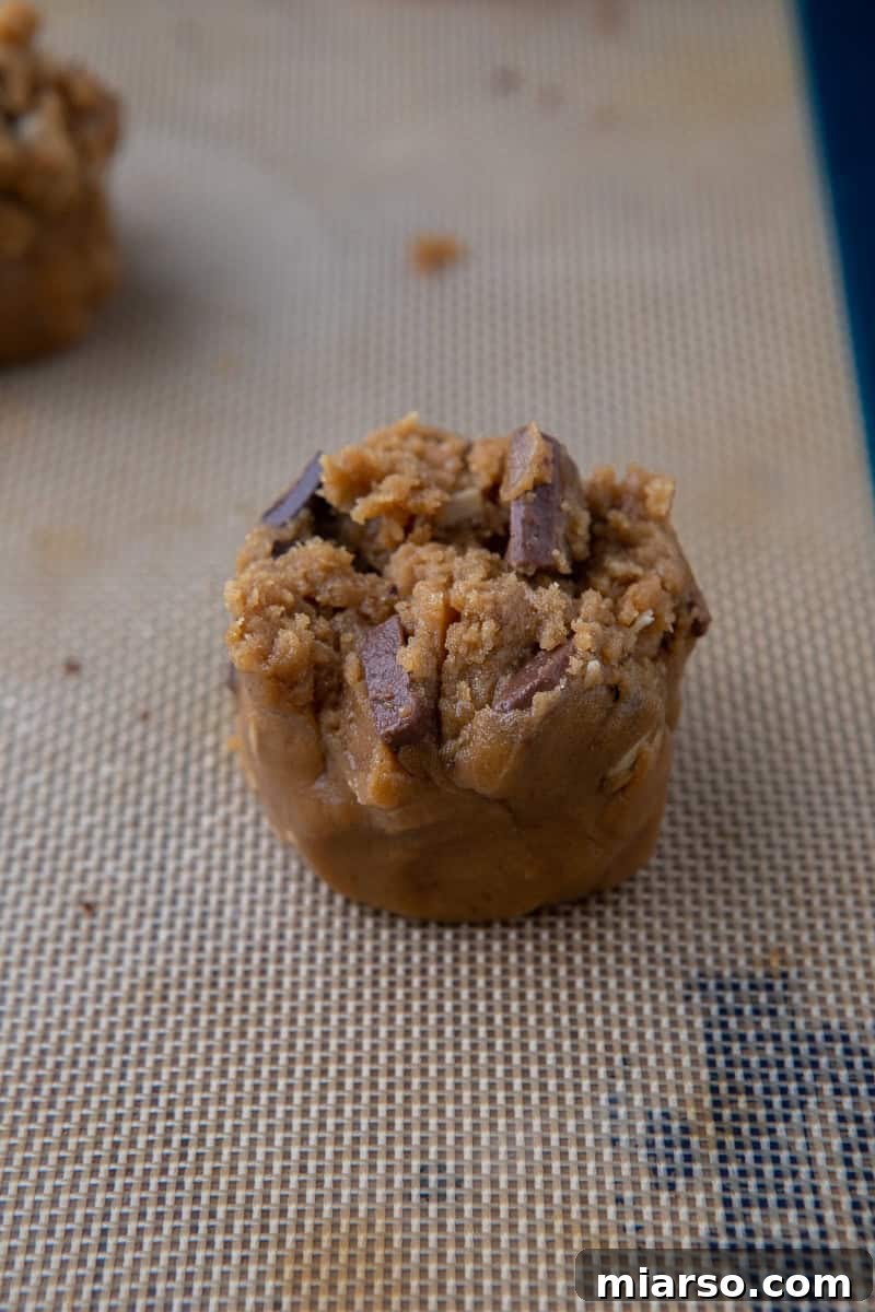 Scooped portions of cookie dough arranged on a parchment-lined baking sheet, prepared for the oven.