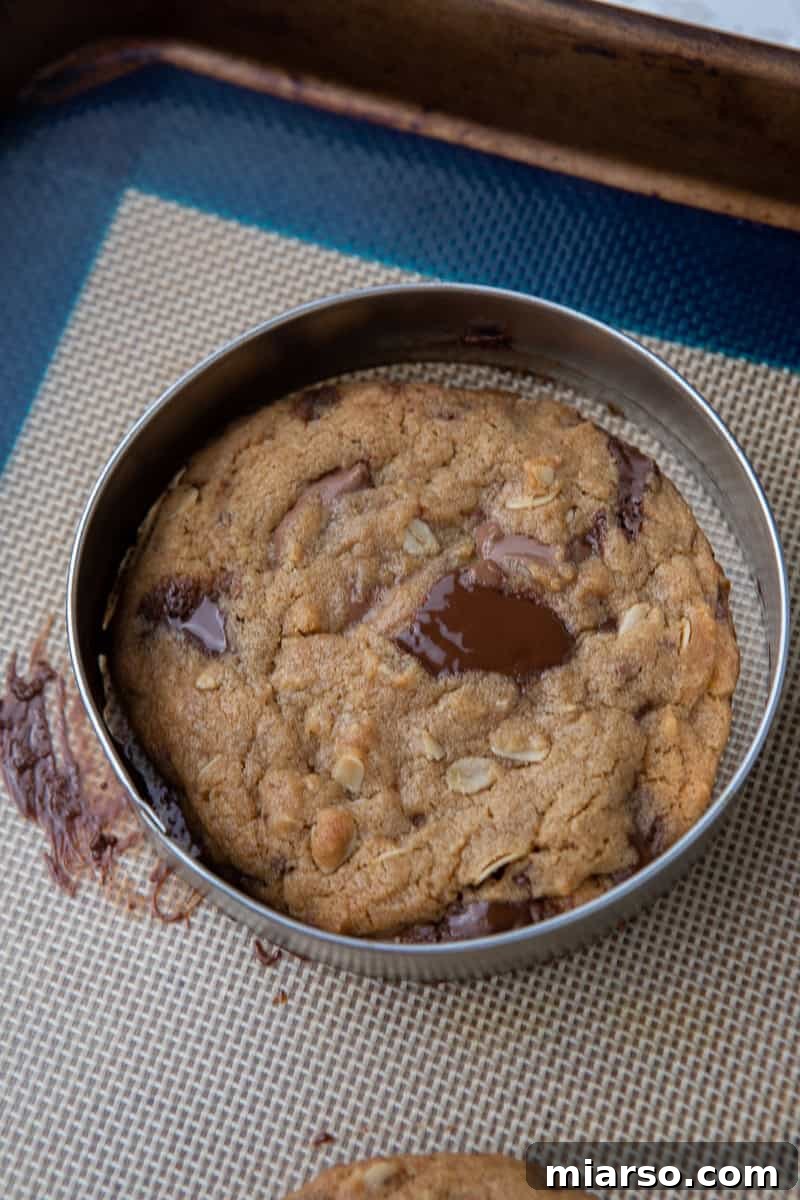 Freshly baked Chick-fil-A cookies on a baking sheet, with a round cookie cutter used to perfect their shape.