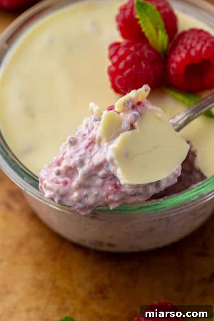 Close-up of a cup of white chocolate raspberry overnight oats with a perfect white chocolate layer on top.